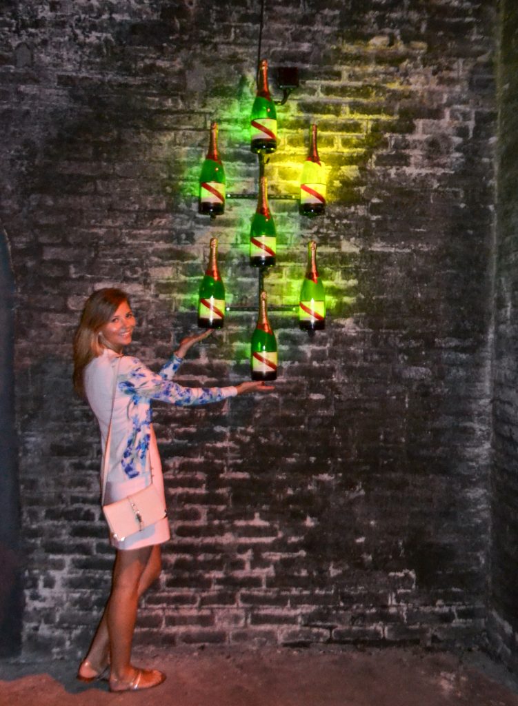 A girl standing next to champagne bottles in G.H.Mumm Champagne cellars