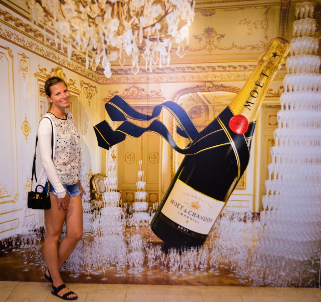A girl standing in front of a Moet & Chandon poster at Moet & Chandon champagne house in France
