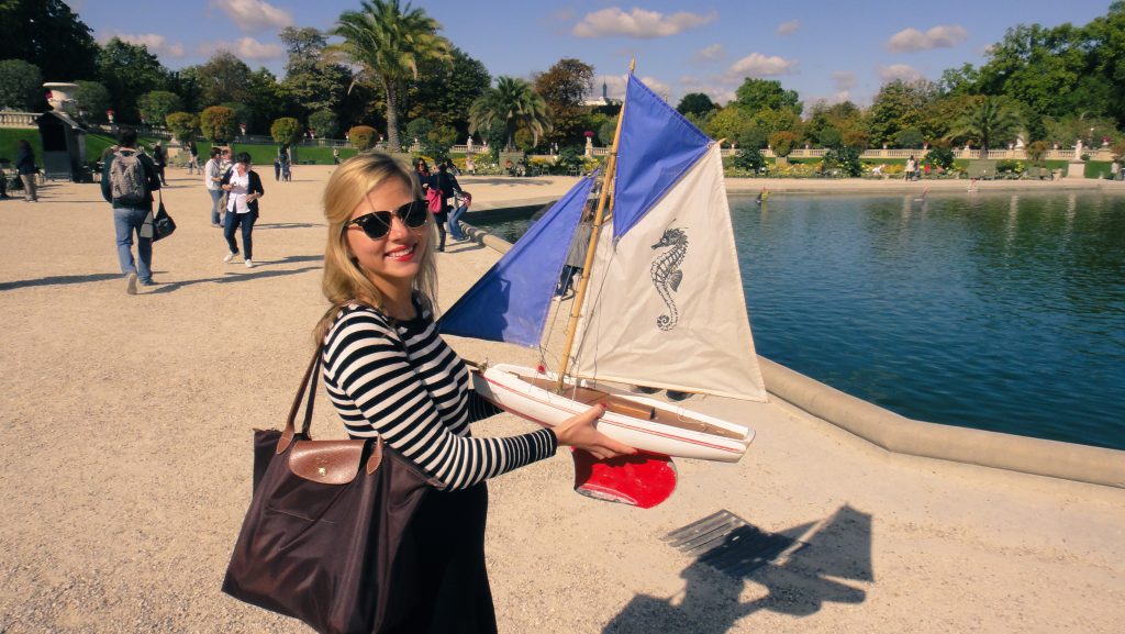 A girl holding a mini sailboat in Jardin du Luxembourg in Paris
