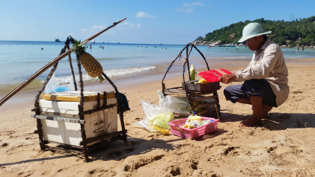 A man selling pineapple on the beach in Thailand