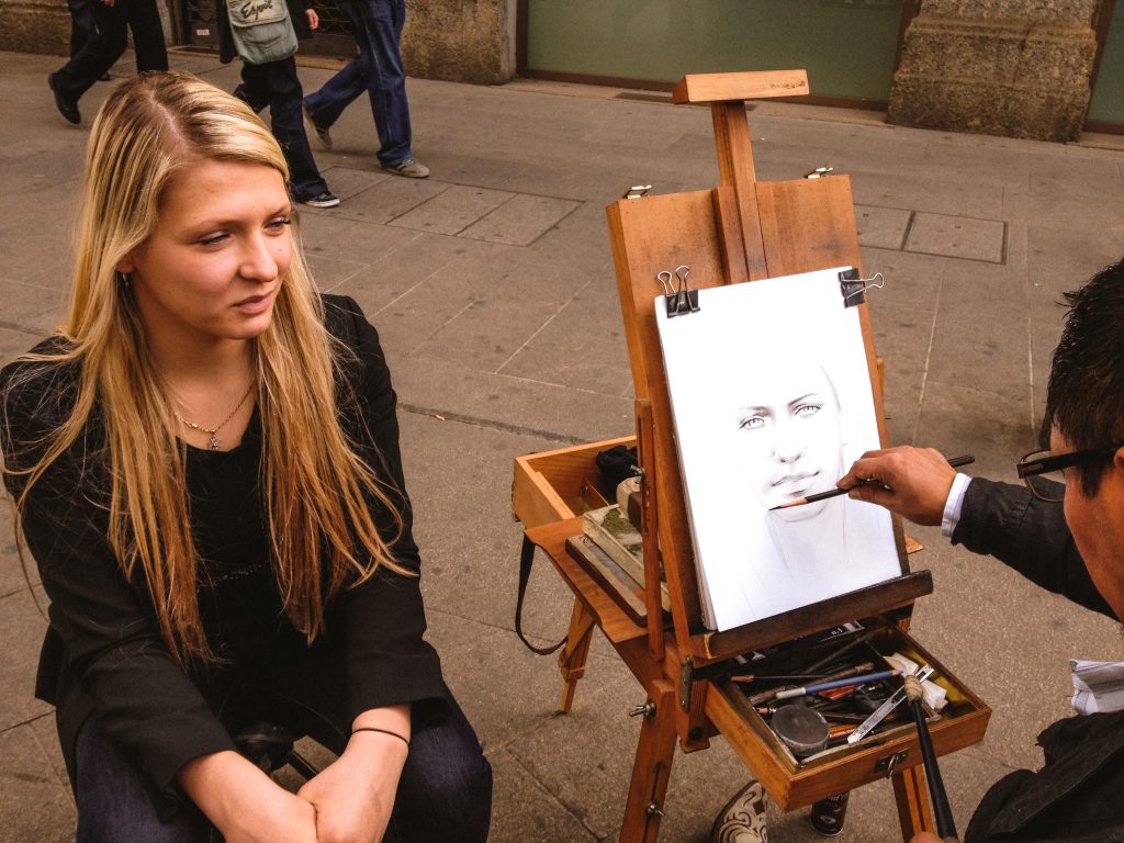 A girl is getting her portrait drawn