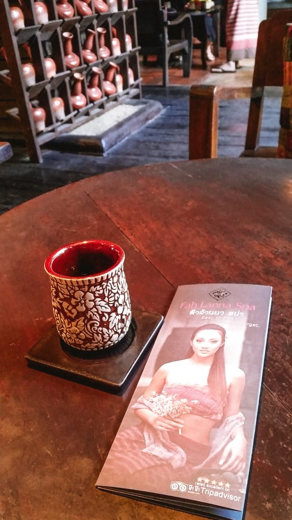 A cup of tea and a leaflet on a table at Fah Lanna Spa in Chiang Mai
