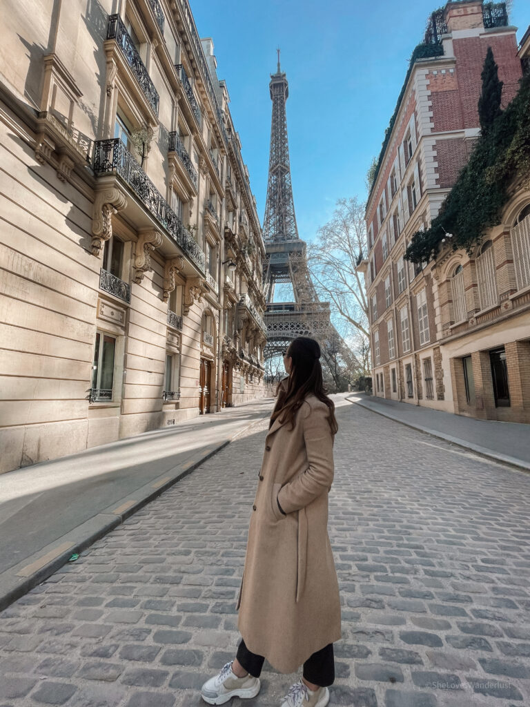 A girl standing in front of Eiffel Tower - How to Spend a Day in Paris